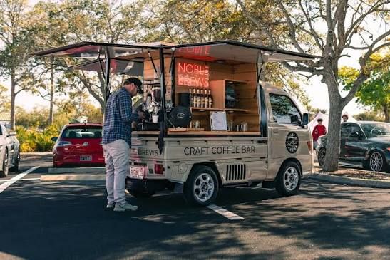 A craft coffee truck serving drinks beneath its open canopy